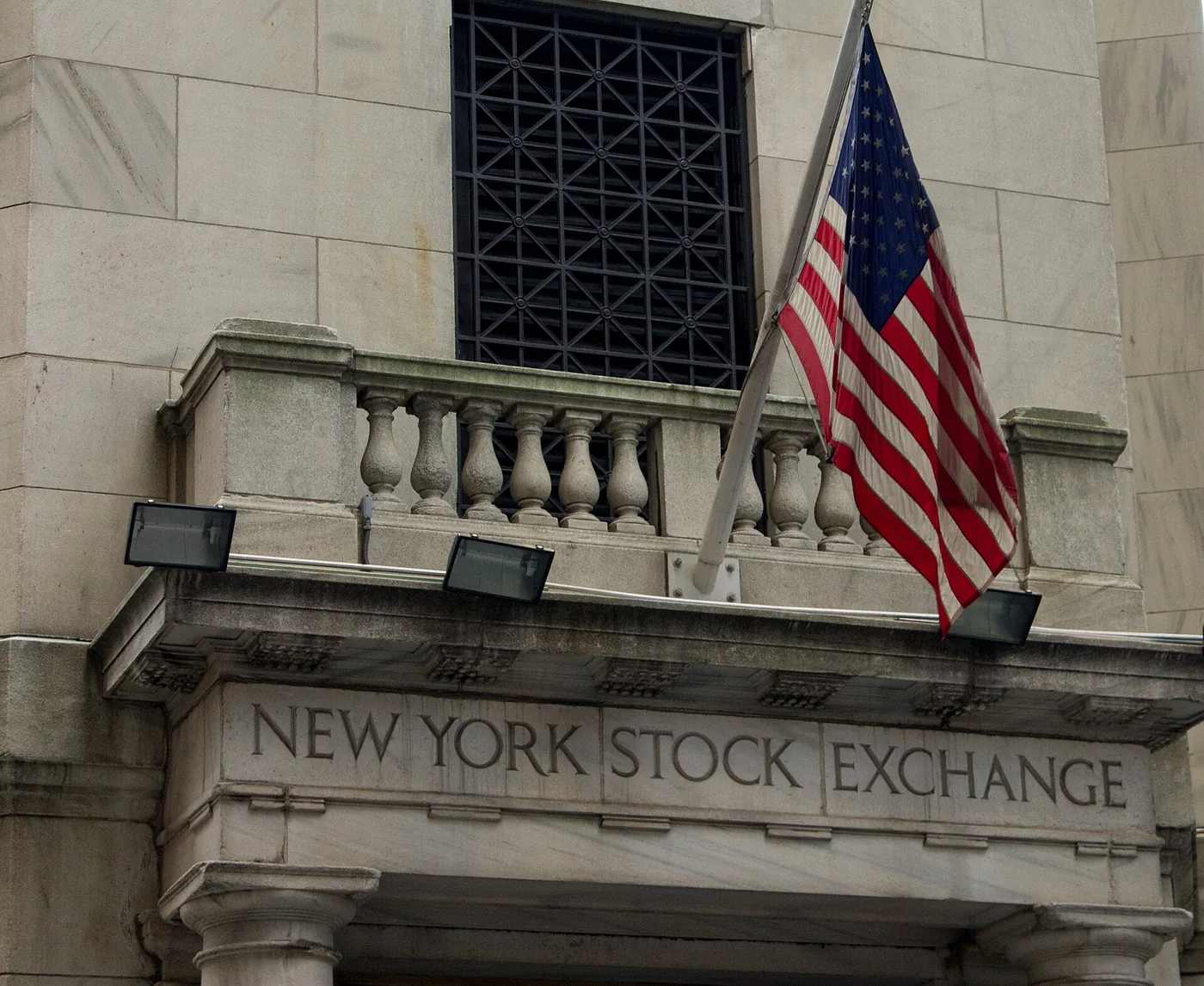 Stone lettering for the New York Stock Exchange above the entrance, with a hanging flag.