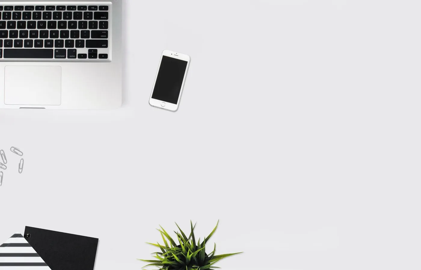 No copyright restriction A silver laptop, a dark smartphone, and notebooks on a pale desk.