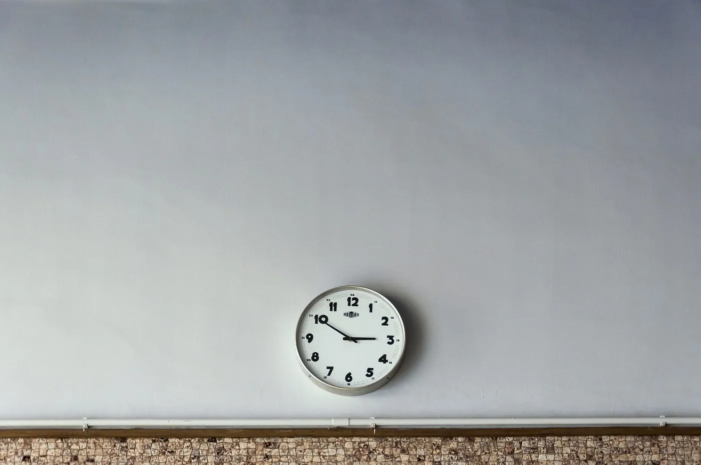No copyright restriction A round analog wall clock with black numerals on a pale wall.